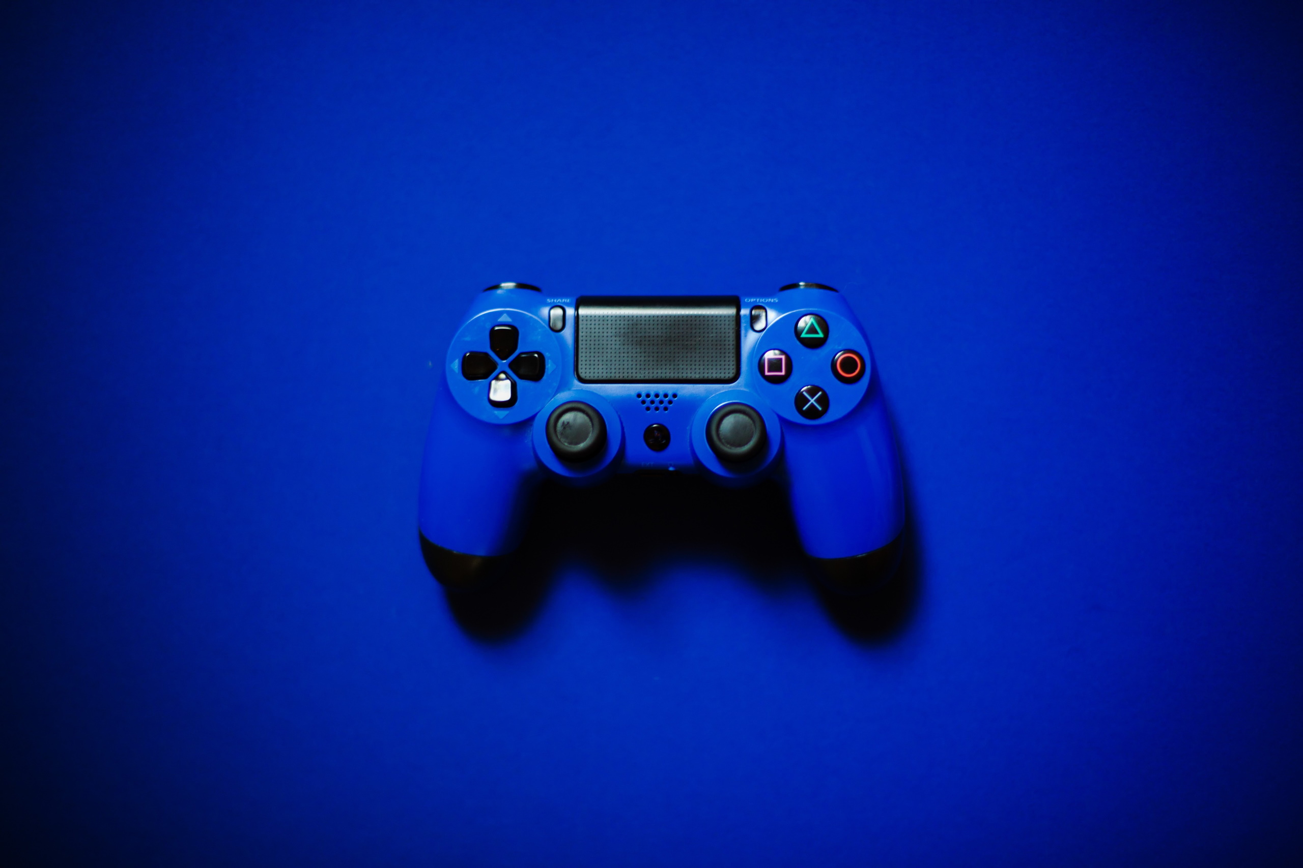 Blue PlayStation controller under blue background