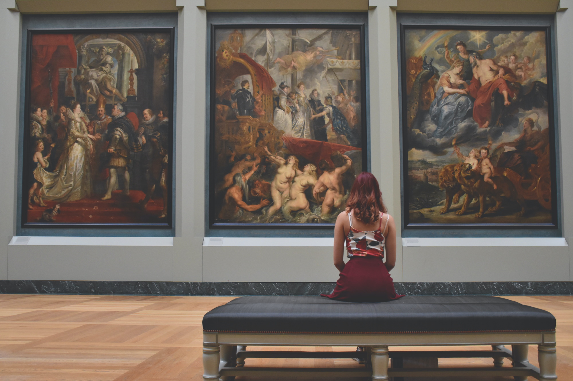 Woman standing on bench watching art museum paintings display