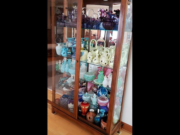 A curio cabinet full of Fenton Glass